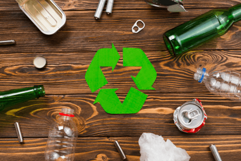 A recycle sign on a wooden surface with plastic bottles around it.
